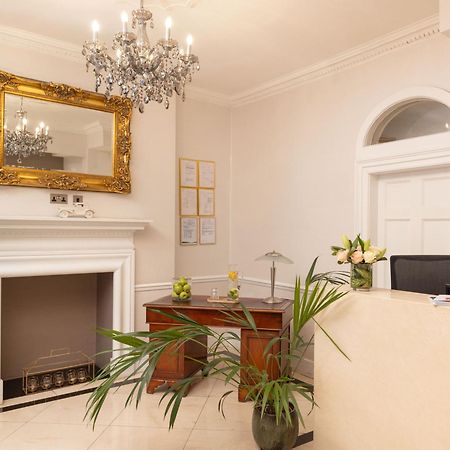 ホテル Montcalm Brewery Townhouse ロンドン エクステリア 写真 The photo shows a stylish reception area. There is a decorative chandelier hanging from the ceiling, providing elegant lighting. A large, ornate mirror is mounted on the wall beside the fireplace, which features a simple, classic design. In front of 