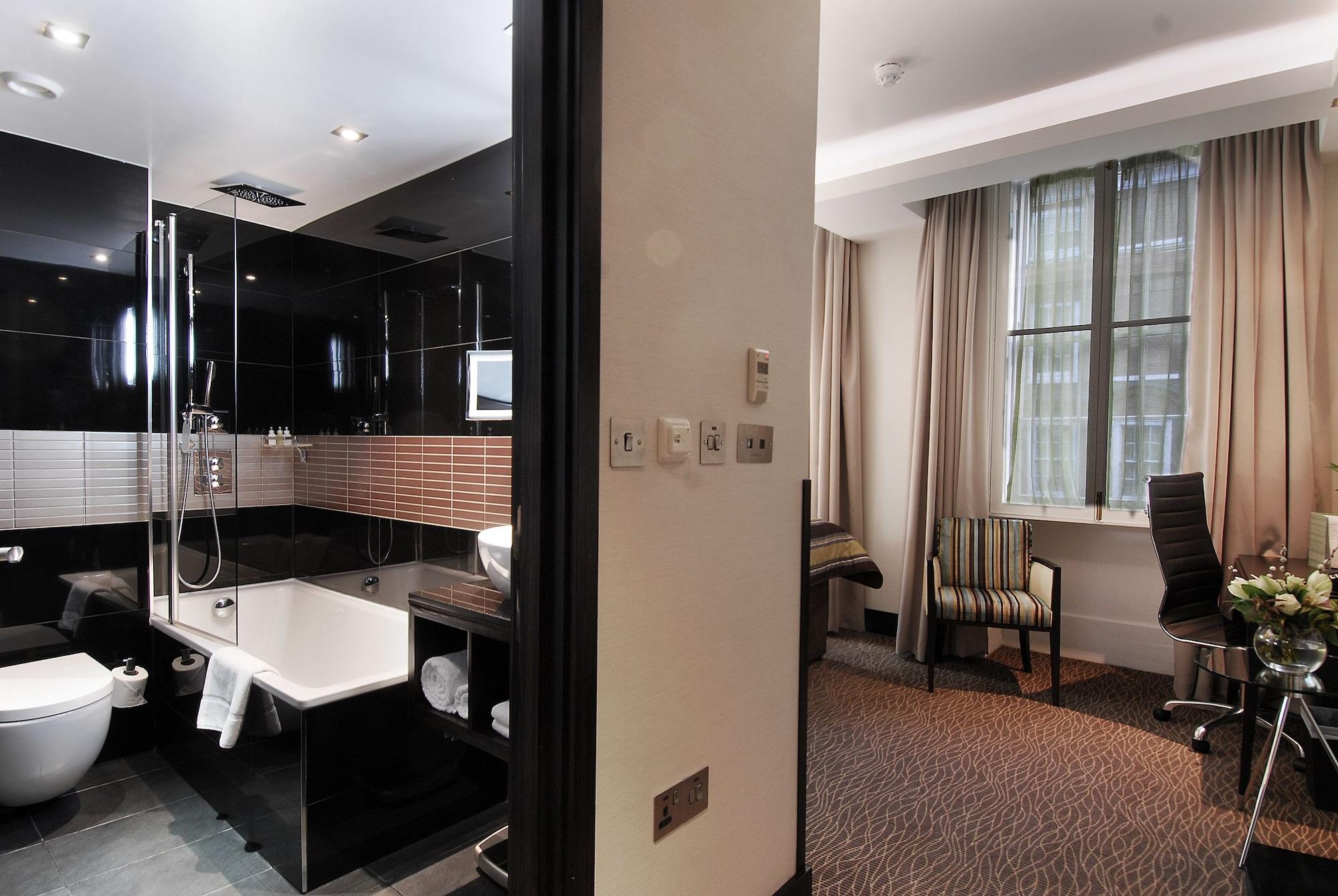 ホテル Montcalm Brewery Townhouse ロンドン エクステリア 写真 The photo shows a modern hotel room that features an elegant bathroom on one side and a living area on the other. 

1. **Bathroom**: The bathroom is stylishly designed with a combination of black and white tiles. It includes a bathtub, a shower area 