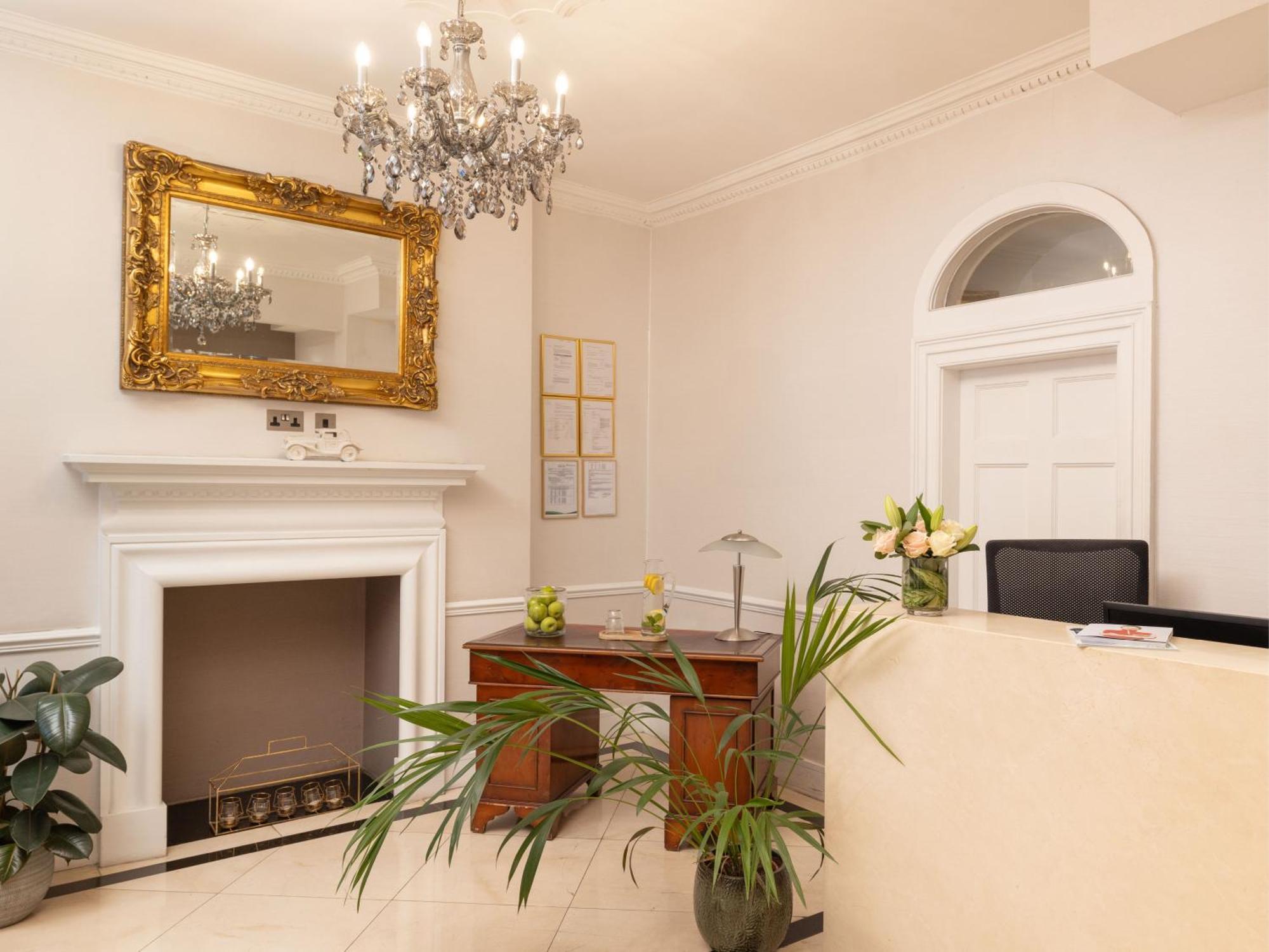 ホテル Montcalm Brewery Townhouse ロンドン エクステリア 写真 The photo shows a stylish reception area. There is a decorative chandelier hanging from the ceiling, providing elegant lighting. A large, ornate mirror is mounted on the wall beside the fireplace, which features a simple, classic design. In front of 