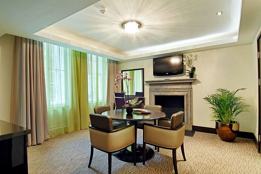 ホテル Montcalm Brewery Townhouse ロンドン エクステリア 写真 The photo shows a well-furnished room, likely a hotel suite or a modern living space. It features a round dining table with four comfortable chairs. The walls are adorned with light-colored decor, and there are large windows with sheer and solid curt