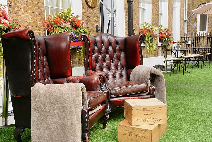 ホテル Montcalm Brewery Townhouse ロンドン エクステリア 写真 The photo depicts two large, elegant armchairs with a classic design, featuring rich burgundy leather upholstery and button tufting. They are positioned in a cozy outdoor setting, with lush green artificial grass beneath them. Next to the chairs, the